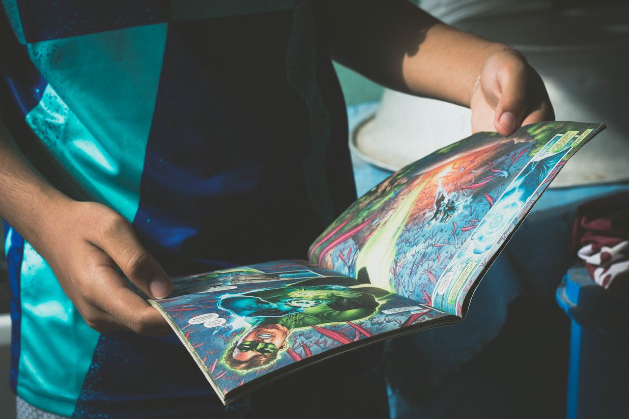 High angle of crop anonymous boy in t shirt reading comic book during weekend at home